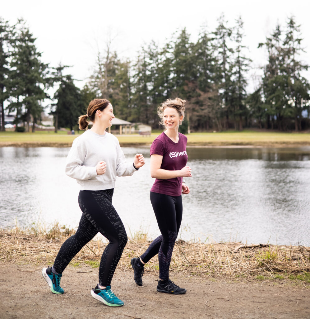 two woman jogging around lake